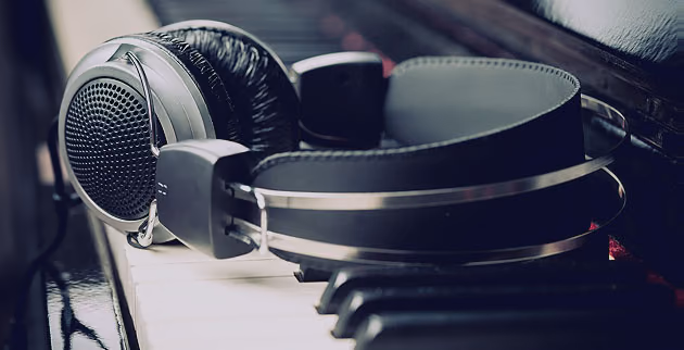 Studio headphones resting on piano keys